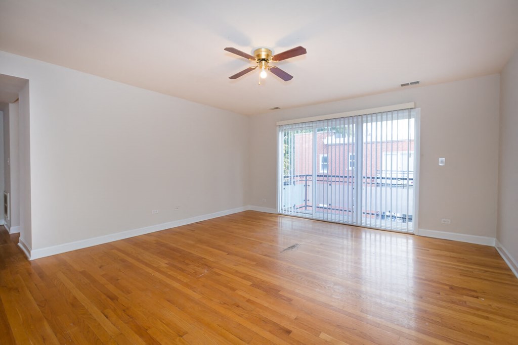 an empty living room with wood floors and a ceiling fan