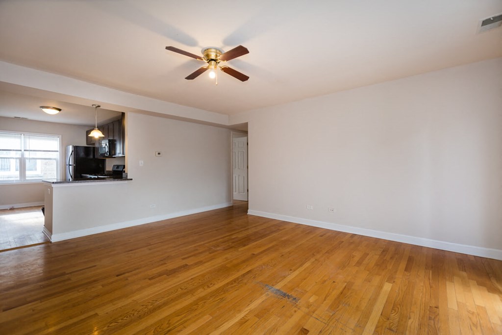 an empty living room with wood floors and a ceiling fan