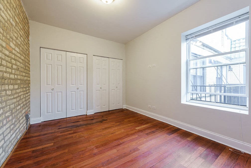 an empty living room with wood floors and a window