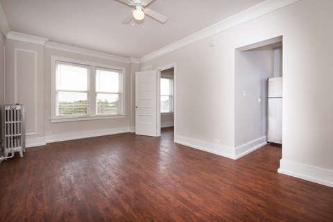 an empty living room with wood floors and a ceiling fan