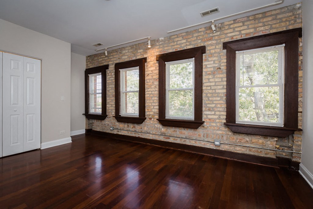 an empty living room with a brick wall and wooden floors