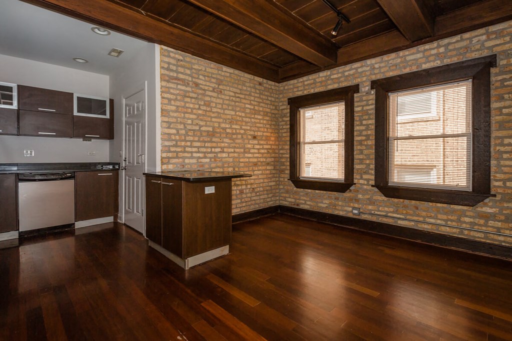 an empty living room with wood floors and brick walls