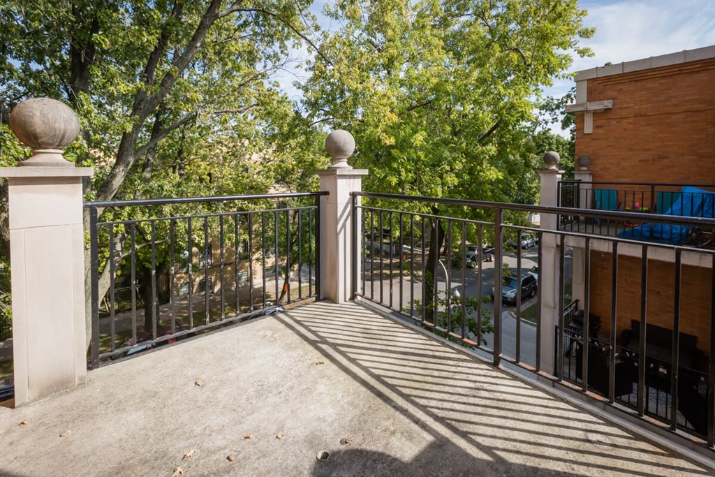a balcony with a metal railing and trees