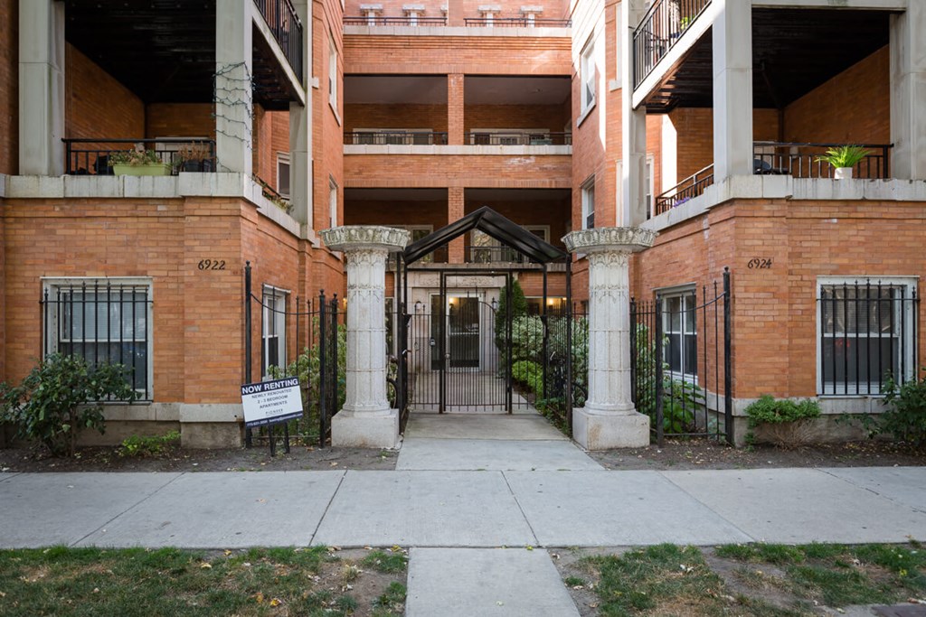 the entrance to an apartment building with a sidewalk and a gate