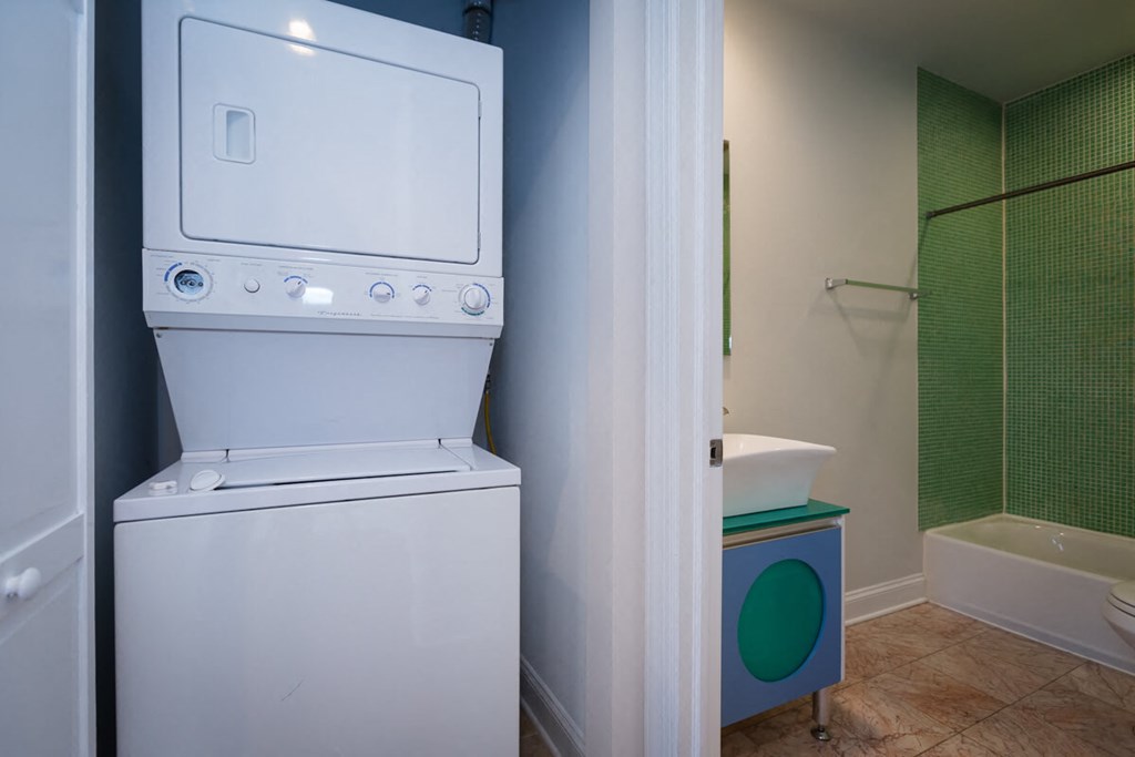 a washer and dryer in a bathroom with a sink and a tub