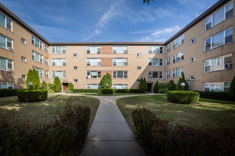 exterior view of a brick apartment building with sidewalks and grass