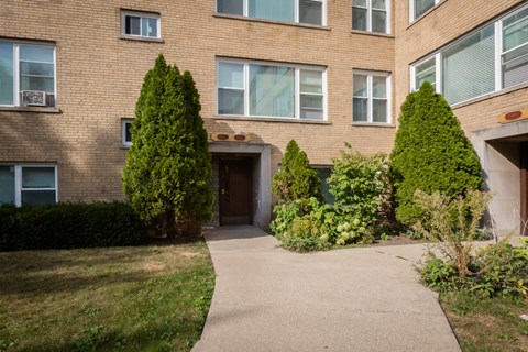 the entrance to a brick apartment building with a walkway and trees