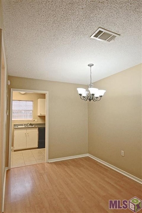 A room with a chandelier and a doorway leading to a kitchen.