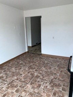 A room with a brown tile floor and a black door.