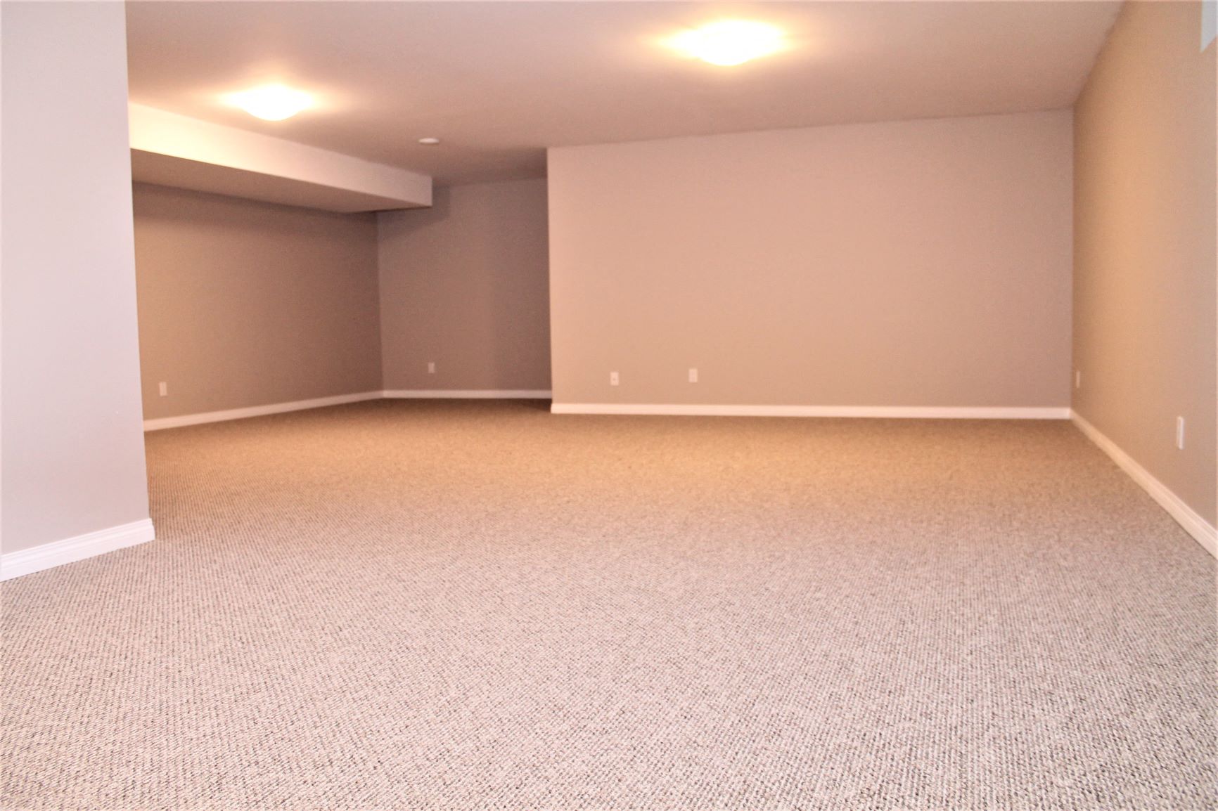 an empty basement with a carpeted floor and gray walls