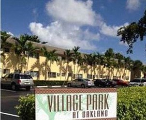 a sign for village park in front of a parking lot
