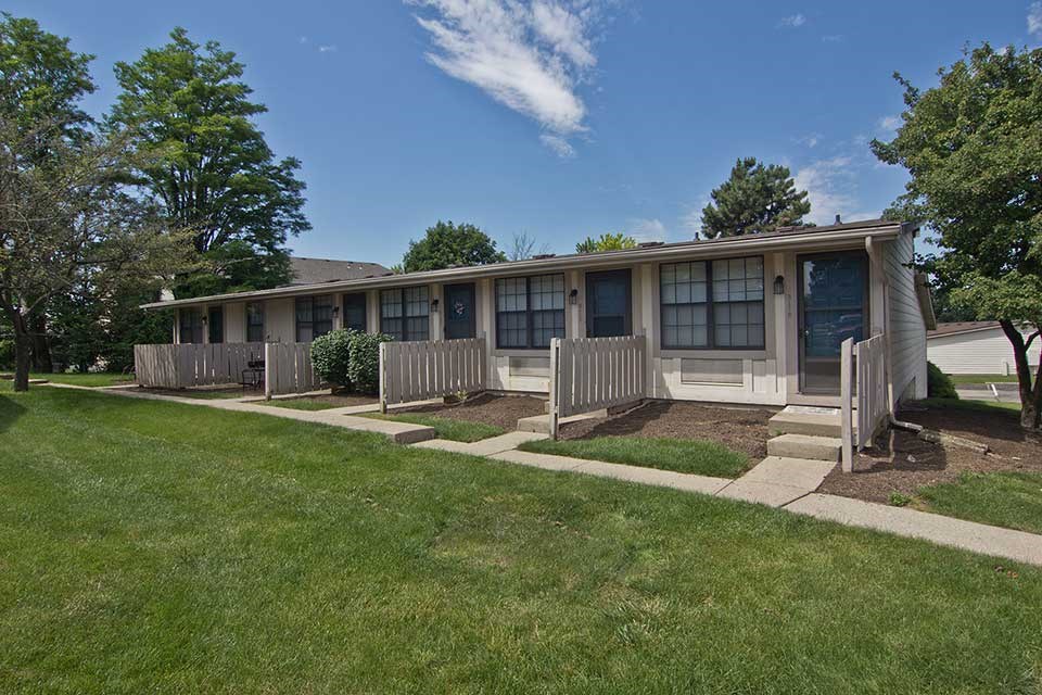 a building with a porch and a lawn in front of it