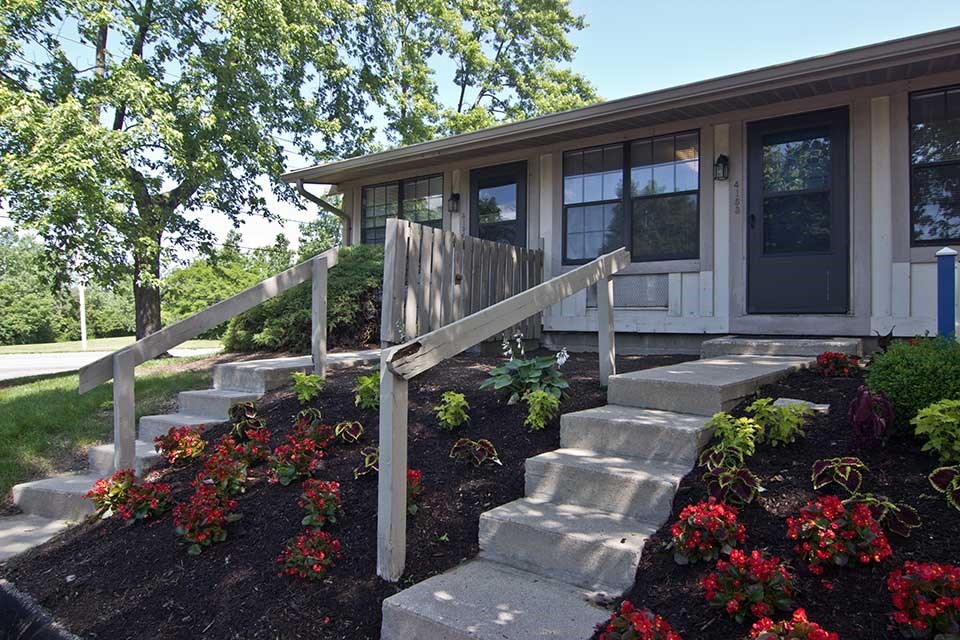 the front of a house with steps and a wooden fence