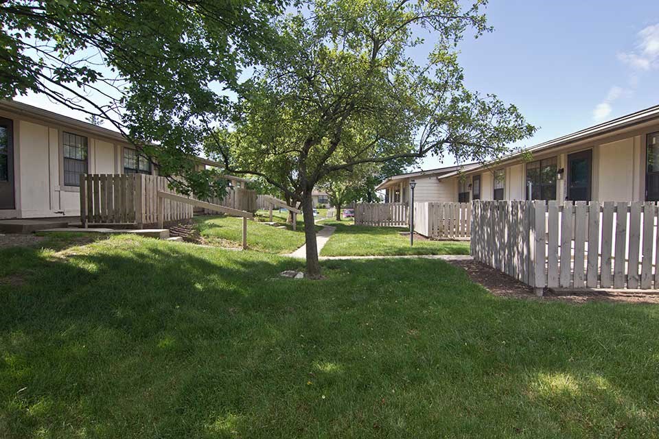 a house with a white fence and a tree in the yard