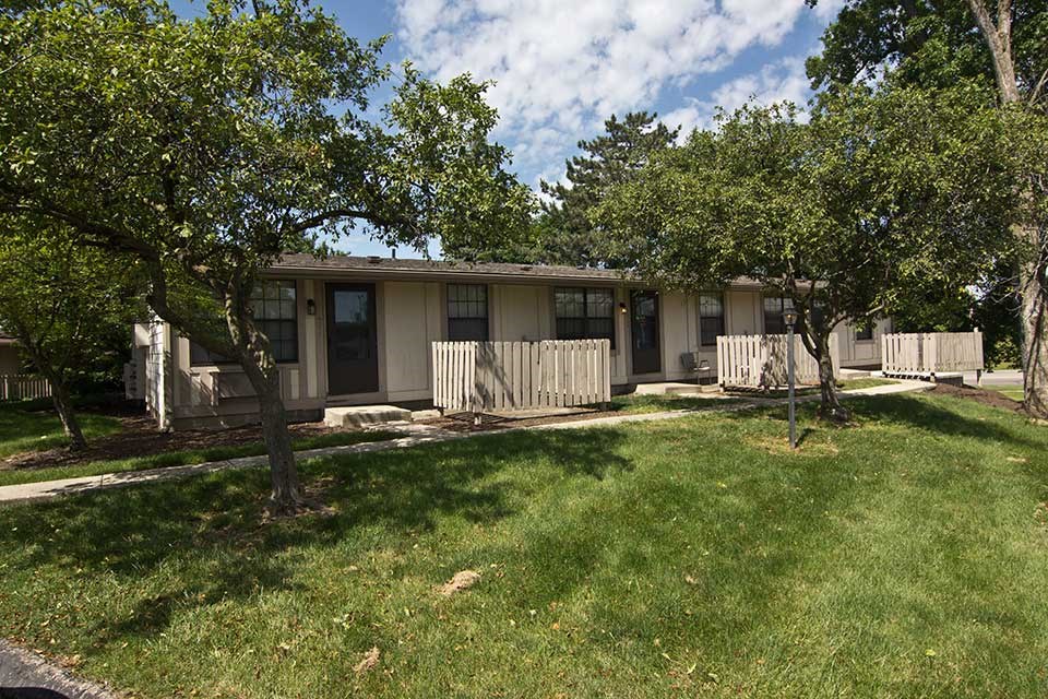 a house with a yard and trees in front of it