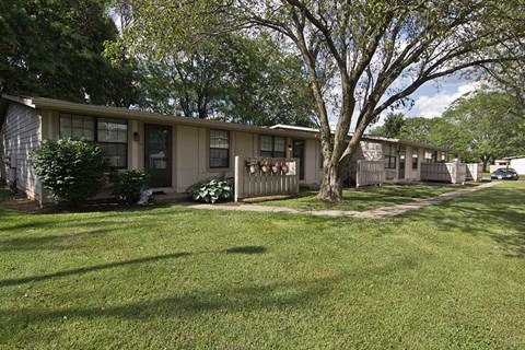a row of houses with a lawn and trees