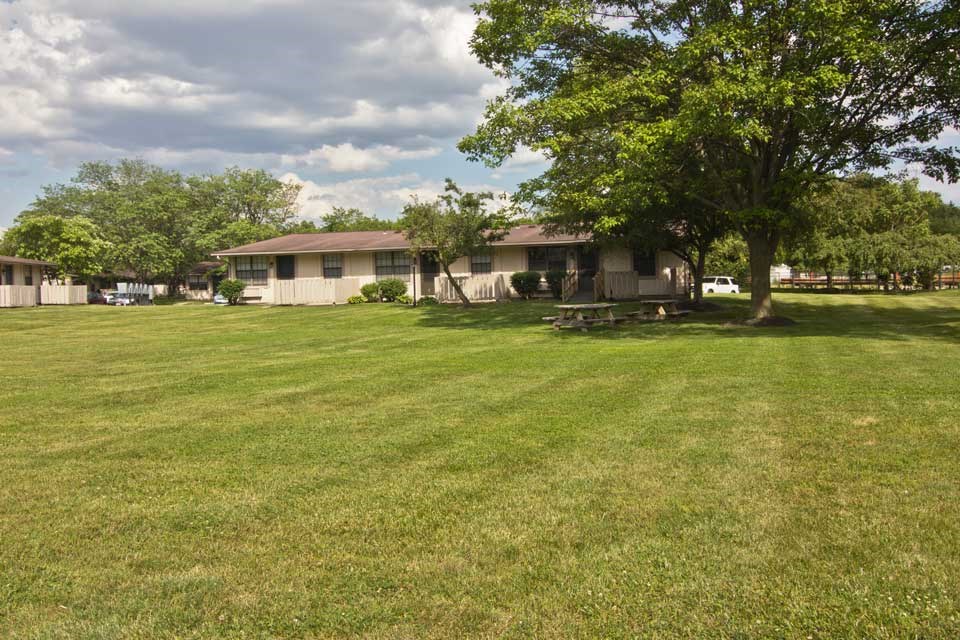 a house with a yard and trees in front of it