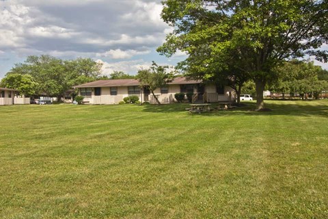 a house with a yard and trees in front of it
