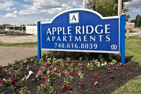 a sign apartments in front of a garden of flowers