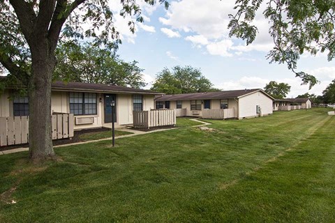a row of mobile homes in a field with a tree