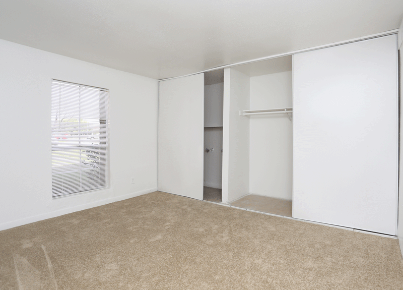 an empty bedroom with a closet and a window
