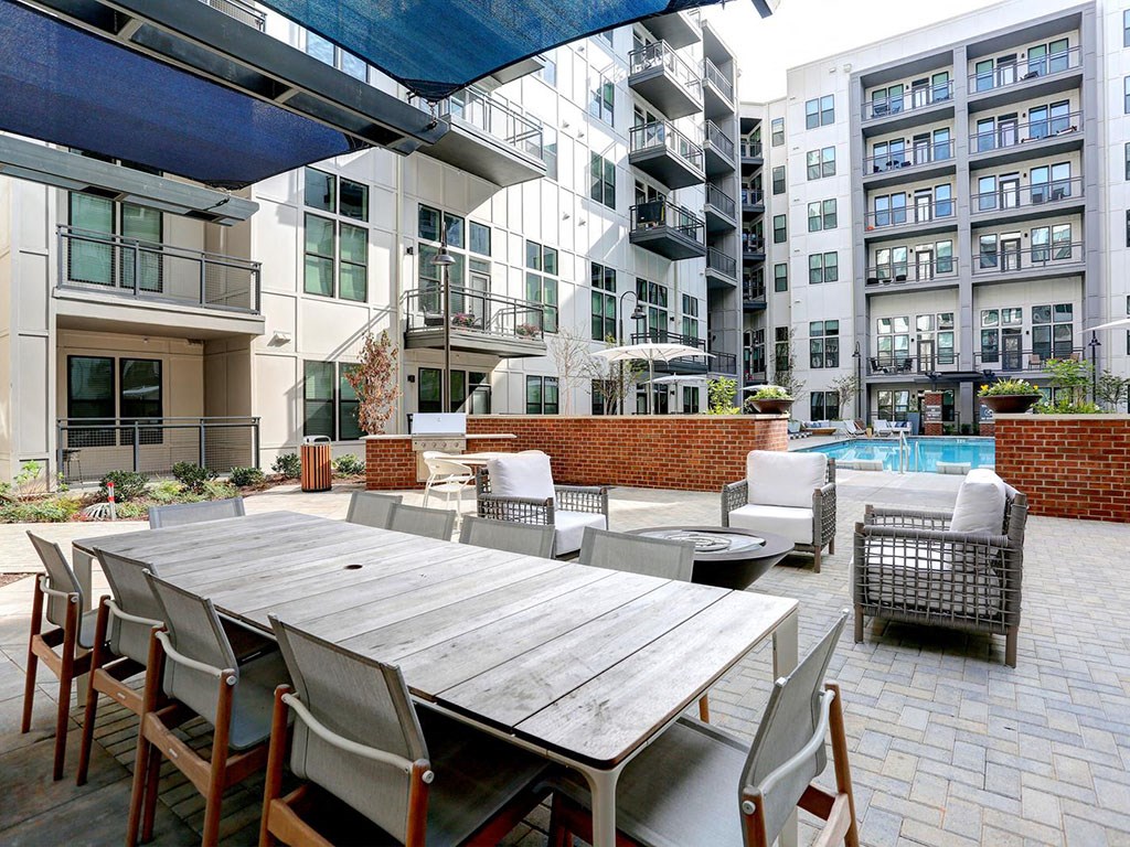 a patio with a table and chairs in front of an apartment building