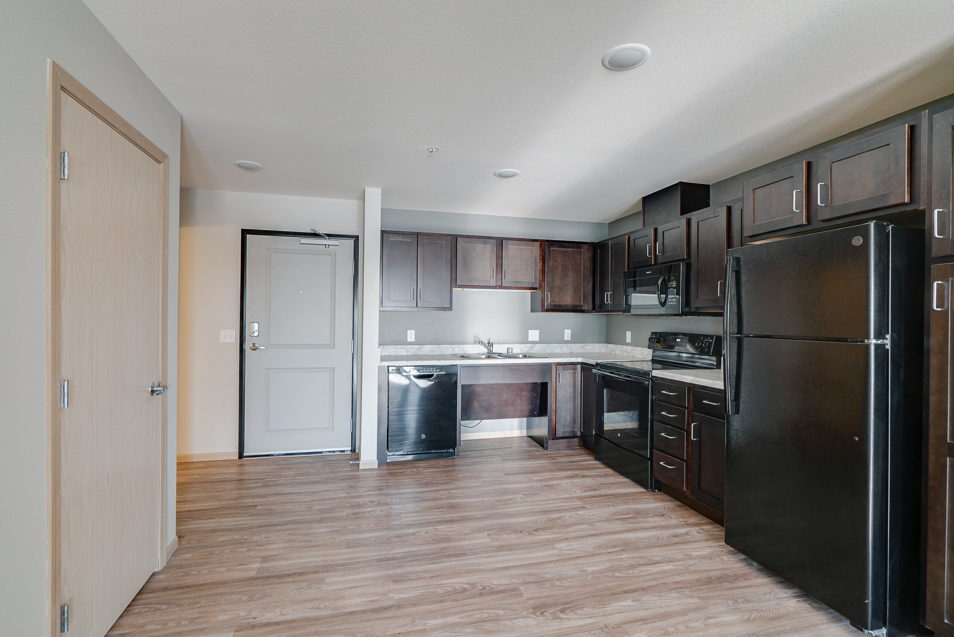 an empty kitchen with black appliances and dark wood cabinets