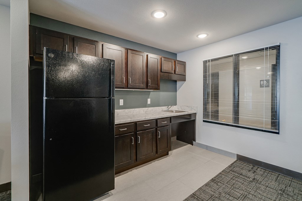 a kitchen with a black refrigerator and wooden cabinets