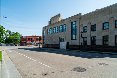 A street view of a city with a building on the right and a clear blue sky.