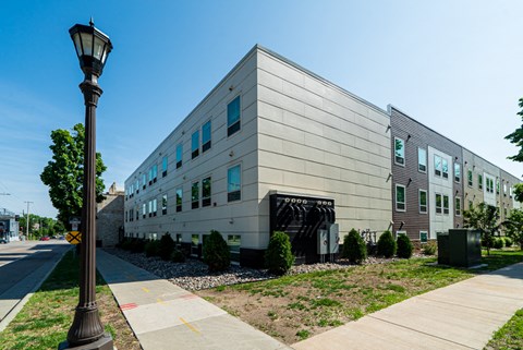 A street lamp stands next to a sidewalk in front of a building.