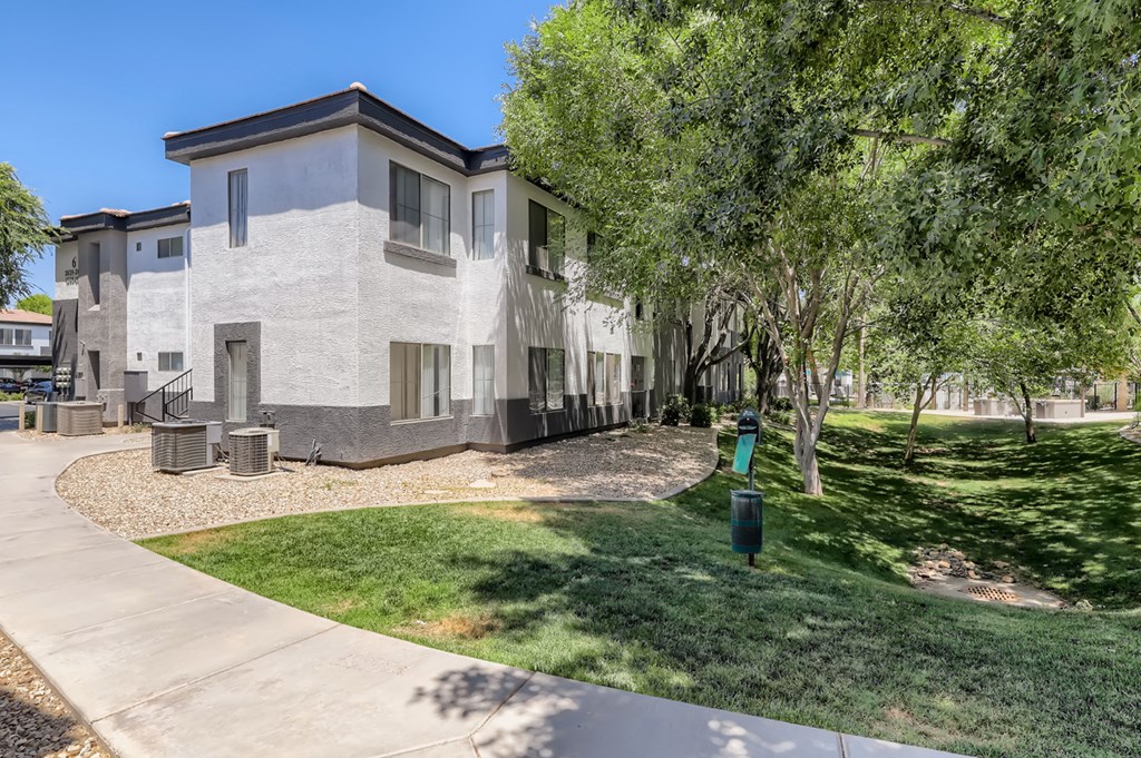 a white building with grass and trees in front of it