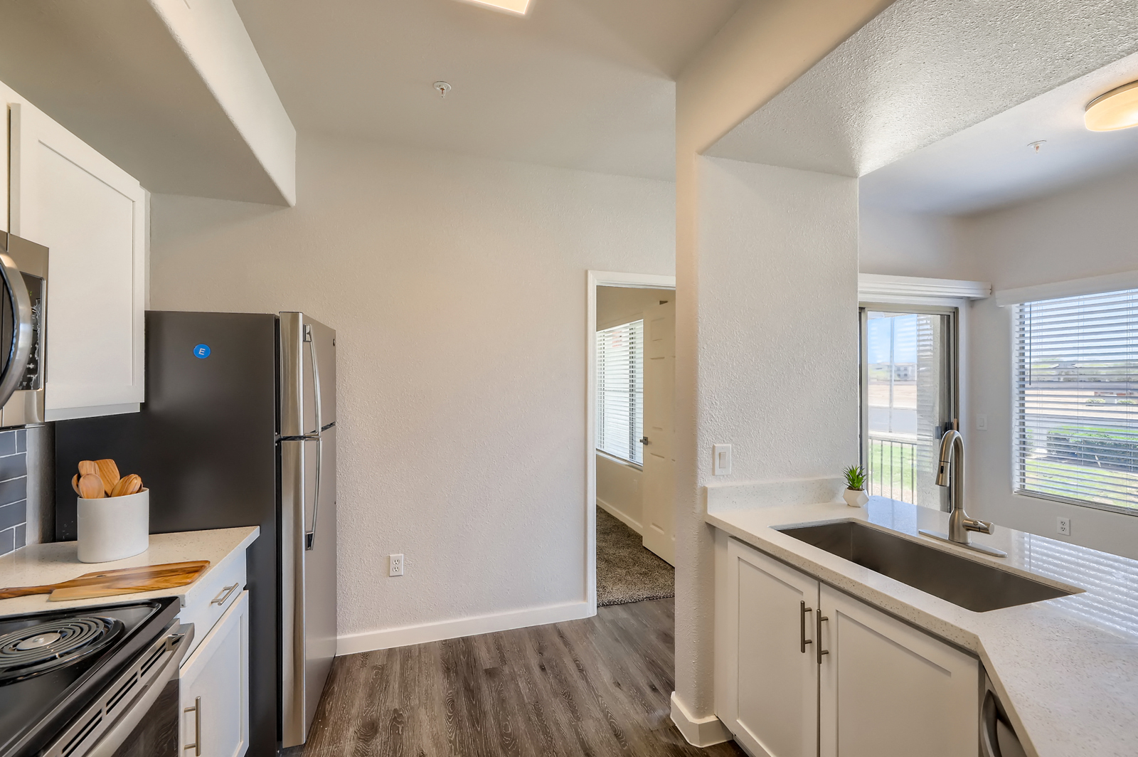 an empty kitchen with white cabinets and a stainless steel refrigerator and sink