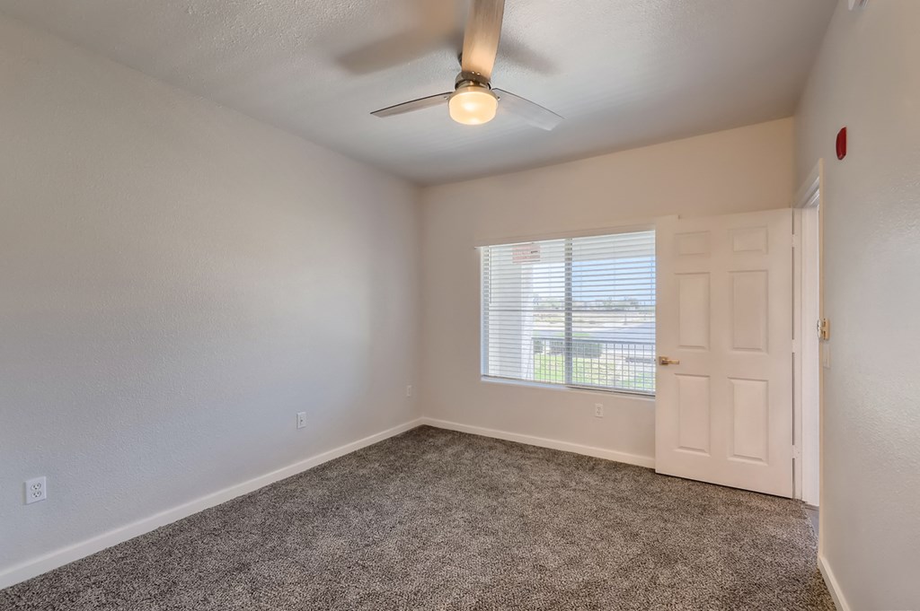 an empty living room with a ceiling fan and a window