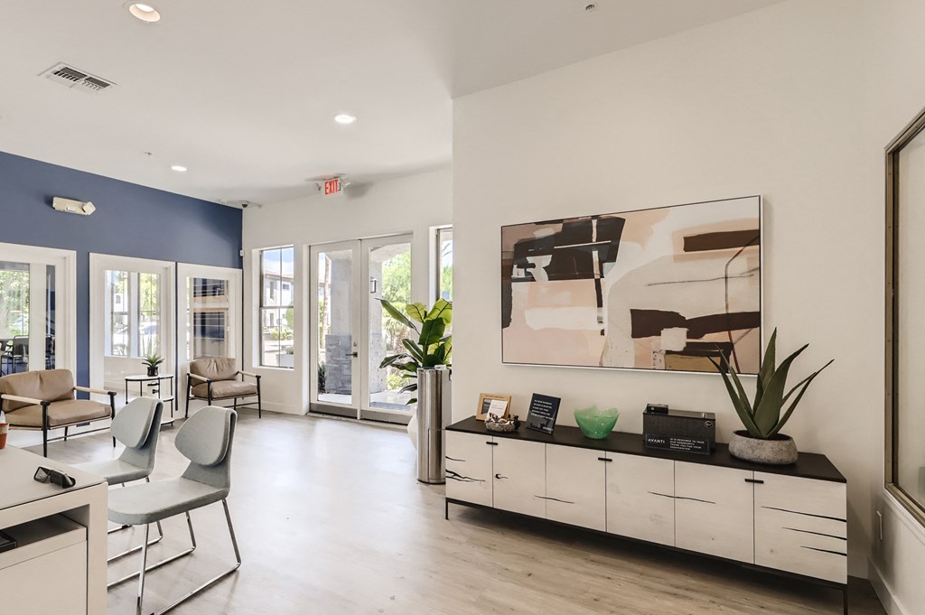 a living room with white furniture and a painting on the wall