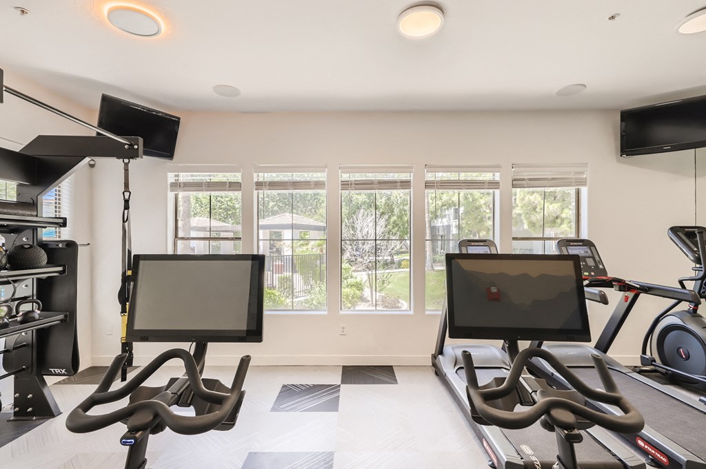 a workout room with cardio machines and a large window