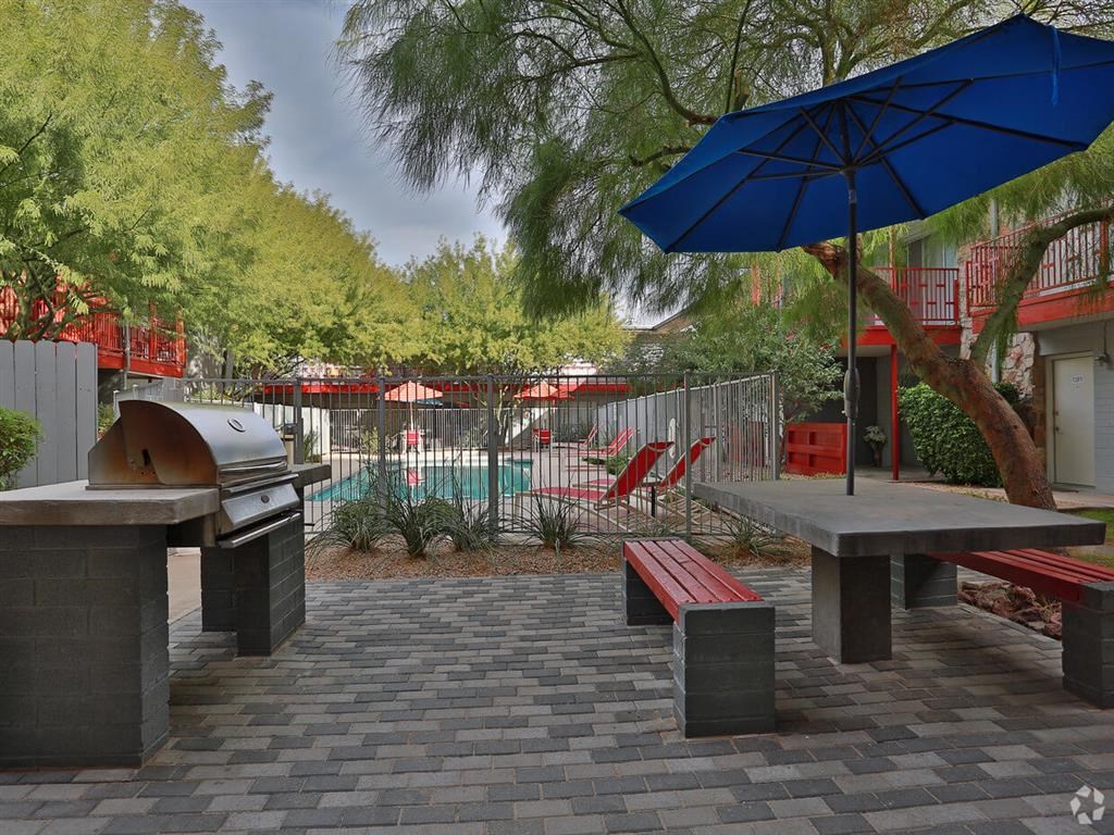 a patio with a grill and tables with umbrellas