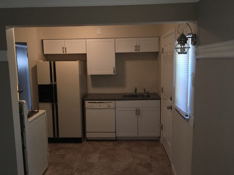 A kitchen with white cabinets and a black fridge.
