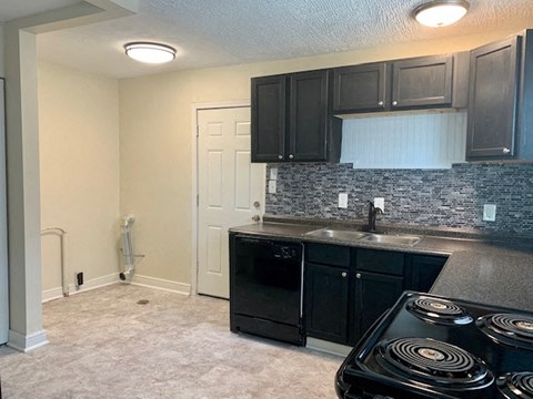 A kitchen with black cabinets and a black stove top oven.