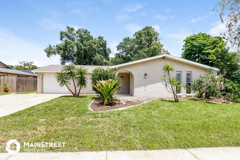 a white house with a lawn and palm trees