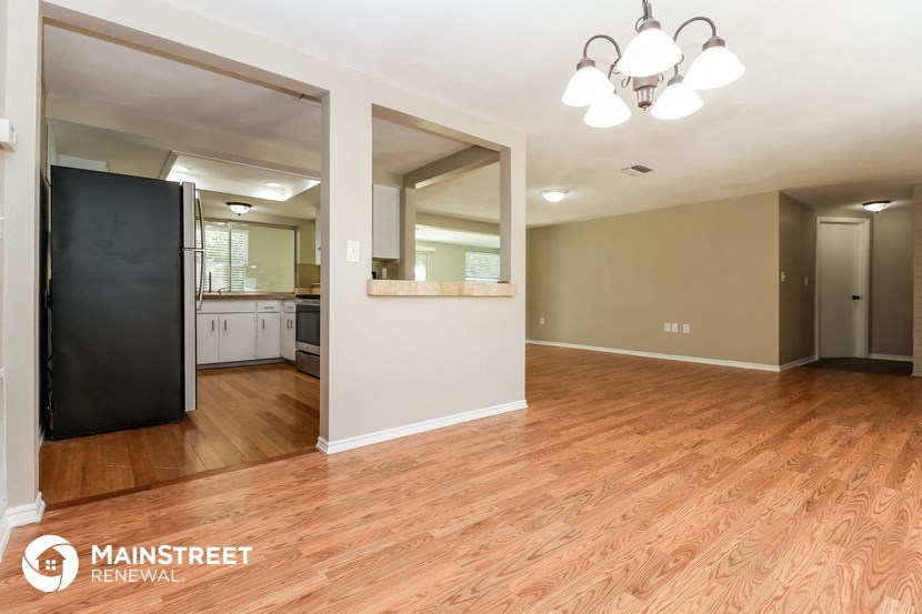 the living room and kitchen of a renovated house with wood flooring