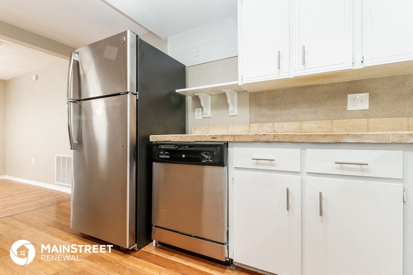 a kitchen with white cabinets and a stainless steel refrigerator