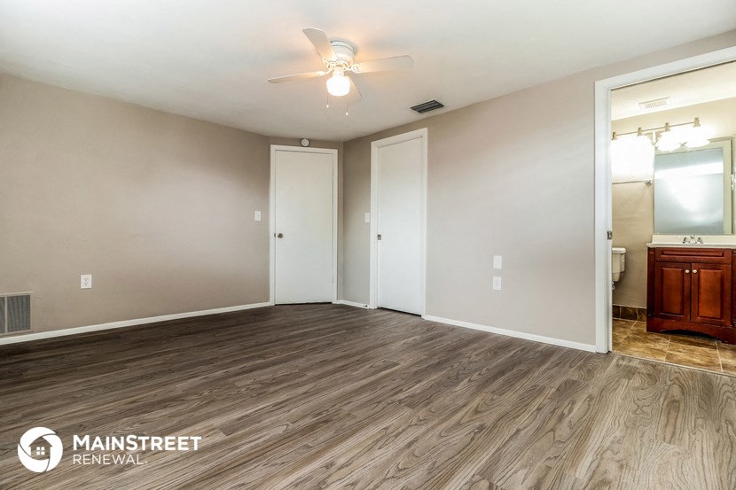 the living room of an apartment with wood flooring and a ceiling fan