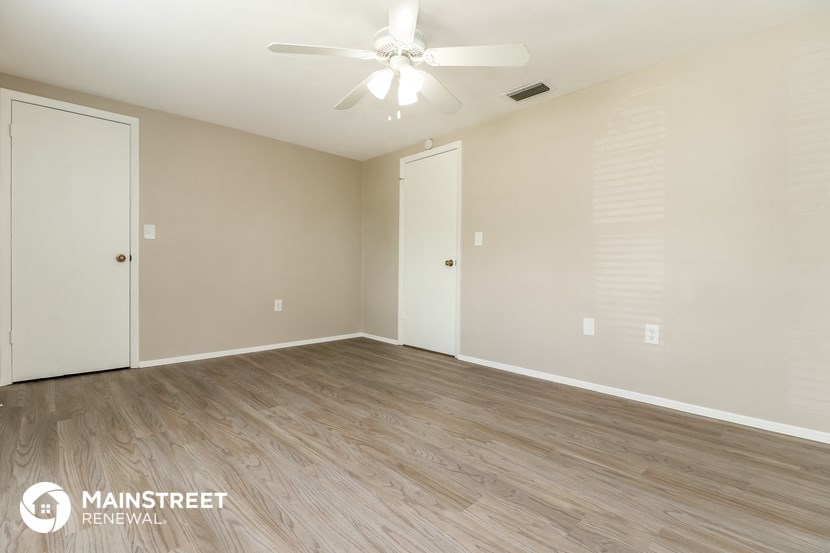 the spacious living room with wood flooring and a ceiling fan