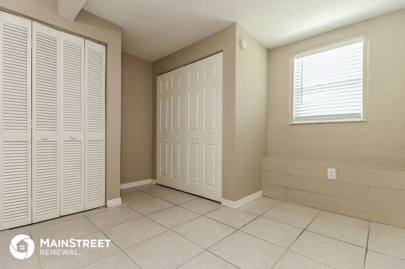 a room with two closets and a tiled floor and a white door