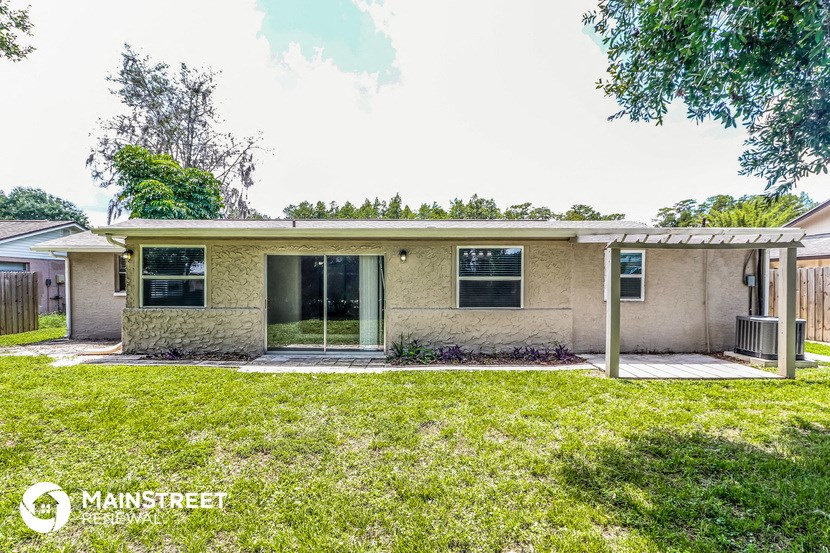 a small beige house with a lawn and a covered porch