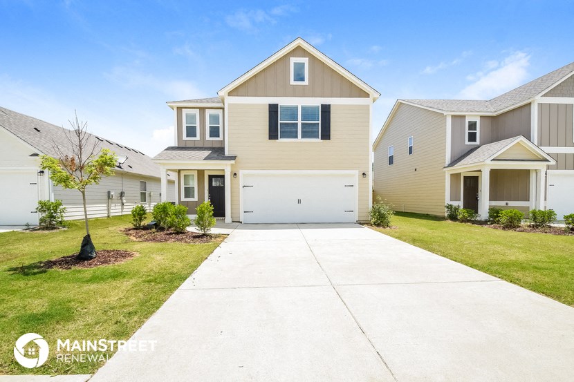 a beige house with a white garage door and a lawn