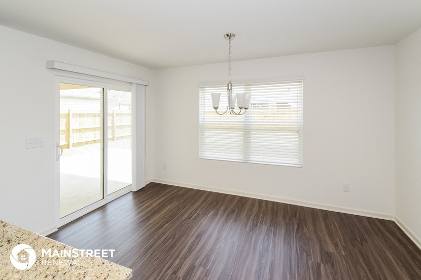 an empty living room with wood floors and a sliding glass door