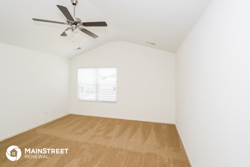 a bedroom with a ceiling fan and white walls and wood floors