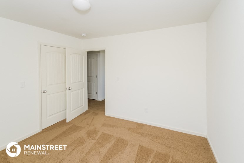 a white bedroom with two doors and a door to a closet