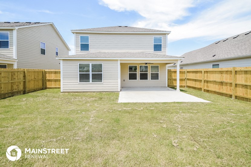 a small white house with a yard and a wooden fence